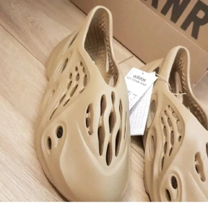 Beige Adidas Yeezy Foam Runner - Säljer ett par beige Adidas Yeezy Foam Runner med unik design. Perfekt för sommaren. Äkta och låda finns med kvitto. 