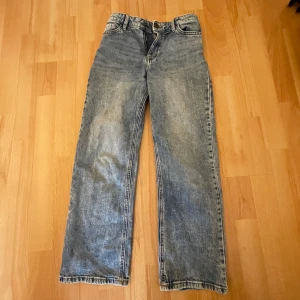 Blå jeans från Lindex - Säljer ett par klassiska blå jeans från Lindex. De har en rak passform och är perfekta för en avslappnad stil. Jeansen har fem fickor och stängs med dragkedja och knapp.