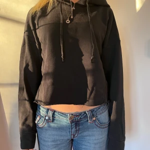 Svart croppad hoodie - Säljer en svart croppad hoodie med långa ärmar och justerbar huva. Perfekt för en avslappnad stil. Passar bra till jeans eller leggings.
