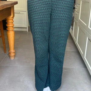 Grönmönstrade byxor från Zara - Snygga gröna byxor från Zara med ett unikt mönster i mörkare nyanser. Byxorna har en rak passform och är perfekta för en stilren look. Tillverkade i ett mjukt material som ger komfort hela dagen.