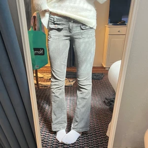 Grå bootcut jeans - Snygga grå bootcut jeans med låg midja och framfickor med lock. Perfekta för en avslappnad stil. De har en klassisk design med en lätt utsvängd passform.