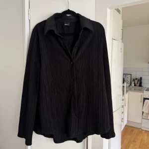 Svart set, top/skjorta och matchande vida byxor - Säljer detga fina set, skjorta i storlek S /M och byxor i storlek M. Snygg svart skjorta med matchande vida byxor, de har ett subtilt randigt mönster. Byxorna har en lös och rak passform och setet tillverkade i ett lätt och bekvämt material. 