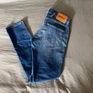 Blå jeans från Replay - Snygga blå jeans från Replay med en riktigt skön Slim passform. Modellen heter ”anbass” och storleken är W29L32. Det finns slitningar vid de främre fickorna men de är fabrikgjorda. Inga defekter finns och jeansen har använts cirka 2 ggr. Inga lappar finns kvar. Butikpris: 1499 Mitt pris: 499!! Skriv gärna vid frågor!