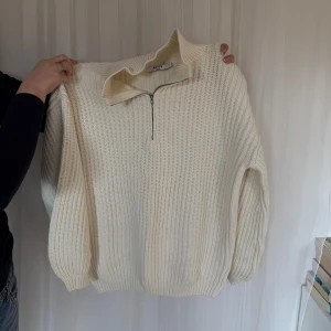 Vit stickad tröja med dragkedja - Säljer en stilren vit stickad tröja från Weekday. Tröjan har en praktisk dragkedja vid halsen och långa ärmar med ribbade muddar. Perfekt för kyliga dagar!