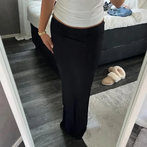Svart långkjol - Snygg svart långkjol med en elegant och enkel design. Kjolen har en tight passform som framhäver figuren och är perfekt för olika tillfällen. Den är tillverkad i ett mjukt och bekvämt material som ger en skön känsla hela dagen. Har blivit ett litet hål men lagats, se sista bilden💓