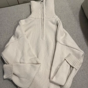 Vit stickad tröja med dragkedja - Säljer en stilren vit stickad tröja med hög krage och dragkedja. Tröjan har långa ärmar och ribbade muddar vid ärmslut och nederkant. Perfekt för kyliga dagar. Pris kan diskuteras och jag är villig till att sänka priset!!!