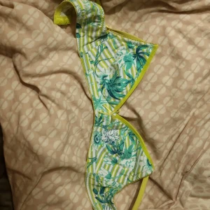 Somrig bh med ränder - Snygg behå från Hema med ett tropiskt blommönster i grönt och blått mot en randig bakgrund. Den har gula kanter och justerbara axelband för perfekt passform. Perfekt för sommaren!