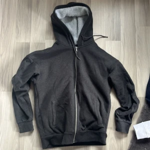 Svart fleecefodrad hoodie från Produkt - Säljer en svart hoodie från Produkt med mjukt fleecefoder. Den har en dragkedja framtill och en rymlig huva. Perfekt för kyliga dagar. 🖤