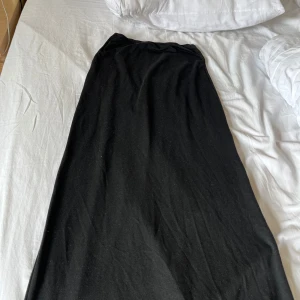 Svart långkjol - Snygg svart långkjol med en tight passform. Perfekt för en stilren look. Kjolen är enkel och mångsidig, vilket gör den lätt att matcha med olika toppar.