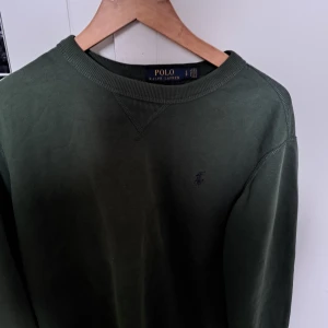 Grön tröja från Polo Ralph Lauren - Säljer en stilren grön tröja från Polo Ralph Lauren. Tröjan har en klassisk design med rund halsringning och diskret logga på bröstet. Perfekt för en avslappnad och snygg look. Skick 9/10. Endast använd ett fåtal gånger