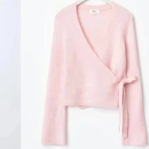 Rosa omlottkofta från Gina Tricot - Säljer en söt rosa omlottkofta från Gina Tricot. Den har en knytning i sidan och långa ärmar. Perfekt för en mysig dag eller en avslappnad kväll. 💖