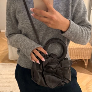 Brun väska med rosett - Säljer en brun väska i fakeläder med rundt handtag och axelrem från &other stories. Inte använd så mycket så den är i bra skick, men lite lite sliten på hörnen. 💓💓Mina egna bilder, köp gärna genom köp nu.
