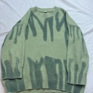 Grön stickad tröja från Kiwi & Co - Säljer en oversized stickad tröja från Kiwi & Co i ljusgrönt med mörkare grönt abstrakt mönster. Tröjan har rund halsringning och långa ärmar med ribbade muddar. Perfekt för lager-på-lager under kyliga dagar.❤️‍🔥❤️‍🔥lite nopprig inte så farligt