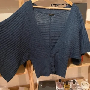 Mörkblå ribbad kofta - Säljer en snygg mörkblå kofta från Reserved. Den är ribbad med stora knappar framtill och har en v-ringad design. Perfekt för att hålla sig varm och stilren. Passar till många olika outfits!