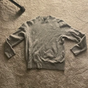 Grå kashmirtröja med rund hals - Mjuk och stilren grå tröja i kashmir med rund halsringning. Passar till det mesta. Långa ärmar och ribbade muddar vid ärmslut och nederkant. Jättemysig och skön. Det står att den är i M men den är liten i storlek så den är S passar den som är runt 170cm