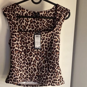 Leopardmönstrad topp från Vero Moda - Säljer en snygg leopardmönstrad topp från Vero Moda med fyrkantig ringning. Toppen är ärmlös och har en tight passform. Snygg att ha bakofram också!Materialet är mjukt och stretchigt för en bekväm känsla.