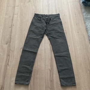 Grå jeansbyxor från Levi's - Säljer ett par grå jeansbyxor från Levi's med klassisk femficksdesign och raka ben. Byxorna har normal passform och är tillverkade i slitstarkt denimtyg. Perfekta för dig som gillar en tidlös stil.