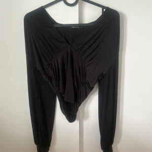 Svart långärmad topp från Nelly - Säljer en svart långärmad topp från Nelly i storlek S. Toppen har dragsko i midjan för en åtsittande passform. Perfekt som festtopp och inga tecken på användning.