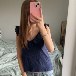 Mörkblå ärmlös blus med volang - Säljer denna super fina mörkblå blusen med volang då den inte kommer till så mycket användning. Den är i bra skick. Storlek M💕