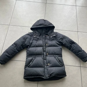 Svart dunjacka med huva - Säljer en svart boomerang jacka. Har sminkfäckar men har inte tvättat jackan så det försvinner med en tvätt. Slitage på ärmen men inget märkvärdigt 