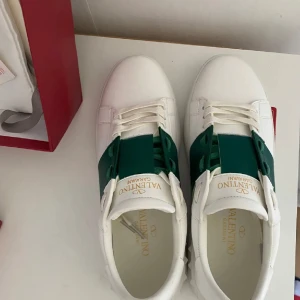 Valentino Garavani vita sneakers med grön detalj - Valentino Open sneakers – gröna (som nya) Säljer ett par Valentino Open i grönt, använda mindre än 10 gånger – i princip nyskick. Originalkartong och kvitto medföljer. Pris kan diskuteras vid snabb affär, tar också emot byten (söker loubs) Skickas inom 24 timmar efter köp.  Skicka dm vid intresse! (Kan sälja för 1750, vid snabb affär , gäller fram tills 27de april)