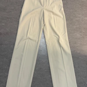 Beige kostymbyxor från Pull&Bear - Säljer ett par stilrena beige kostymbyxor från Pull&Bear i storlek 34. Byxorna har raka ben, hög midja och stängs med knapp och dragkedja. Perfekta för en clean och klassisk look. Är öppen för bud, så det är bara att skicka!💕