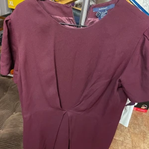 Gant klänning vinröd stl 42 - Säljer en vinröd klänning från GANT i enkel och stilren design. Klänningen har korta ärmar, rund halsringning och dragkedja i ryggen. Passformen är normal och tyget känns mjukt och följsamt. Perfekt för dig som gillar klassiska plagg med modern touch.