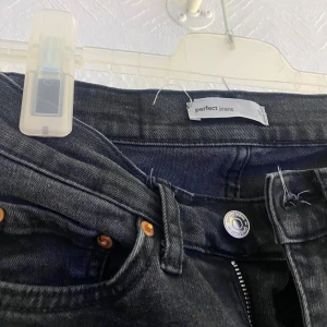 Svarta bootcut jeans från Perfect Jeans - Säljer ett par svarta bootcut jeans från Perfect Jeans. Jeansen har klassisk femficksdesign, knapp och dragkedja framtill samt svarta sömmar. Perfekta för dig som gillar en tidlös och stilren look.