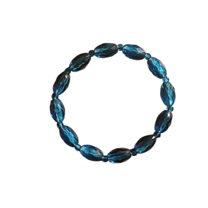 Blått armband med ovala pärlor - Snyggt armband med glittrande blå ovala pärlor. Perfekt för att ge din outfit en färgklick och lite extra bling. Elastiskt band gör det enkelt att ta på och av.