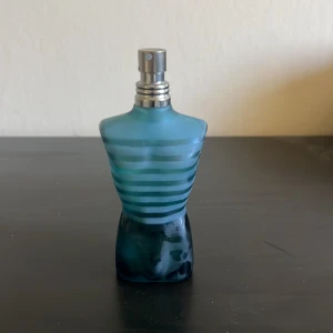 Le Male Eau de Toilette från Jean Paul Gaultier - Klassisk herrparfym i blå, kroppformad flaska med frostat glas och vita ränder. Doften är ikonisk och flaskan har en metallisk spraykork. Perfekt för dig som gillar fräscha och maskulina dofter. flaskan har lite repor, knappast använd och pris diskuteras.