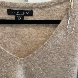 Beige stickad v-ringad tröja från Amisu - Mysig beige stickad tröja från Amisu med v-ringning och långa ärmar. Perfekt för lager-på-lager och passar till många olika outfits. Ribbstickade muddar vid ärmslut och nederkant.