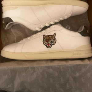 Polo Ralph Lauren Heritage Court Top skor - Säljer ett par vita sneakers från Polo Ralph Lauren med en broderad tiger på sidan.                                 Använt bara ett par gånger.                                       Pris kan diskuteras vid snabb affär.                         *Ordinarie pris: $1595kr*