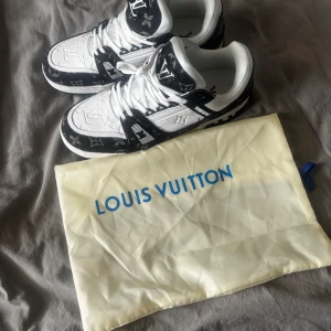 Louis Vuitton sneakers svart/vit - Säljer ett par Louis Vuitton sneakers i svart och vitt med tydliga LV-loggor och monogramdetaljer. Dom är helt oanvända. 