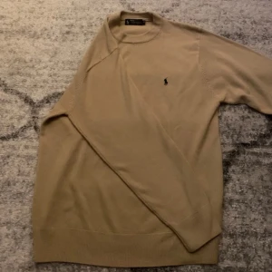 Beige kashmirtröja från Polo Ralph Lauren - Säljer en lyxig beige tröja från Polo Ralph Lauren i 100% kashmir. Tröjan har rund halsringning, lång ärm och den klassiska broderade loggan på bröstet. Perfekt för dig som gillar stilrena och mjuka plagg.