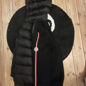 Svart dunjacka med huva från Moncler - Säljer en svart dunjacka från Moncler med huva och moncler märke på sidan. Jackan är i ny skick då den köptes som present men kom ej till användning, skriv för fler bilder. Pris kan diskuteras vid snabb affär