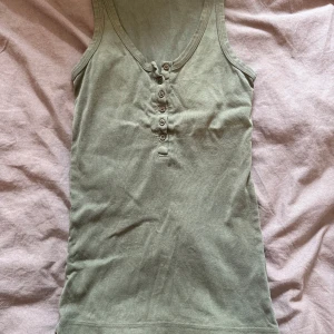 Grön linnetopp med knappar - Snygg grön linnetopp med rundad halsringning. 😍Framsidan har en rad med sex knappar som ger en chill och enkel look. Perfekt att matcha med jeans eller shorts för en avslappnad stil. Står ingen storlek men passar mig med S!❤️