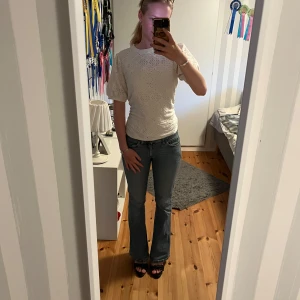 Vit blus med broderade detaljer - Säljer en söt vit blus med korta puffärmar och broderade hålmönster. Blusen har rund halsringning och är i ett luftigt material som passar perfekt till jeans eller kjol. Perfekt för dig som gillar romantisk och stilren look.