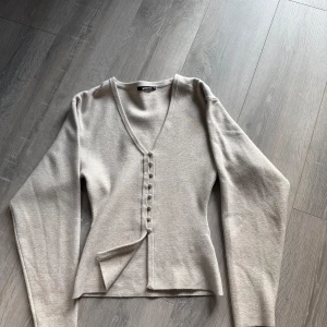 Beige kofta med knappar från Gina Tricot - Superfin beige kofta från Gina Tricot i stickat material. Den har v-ringning, slimfit. Använd typ en-två gånger💞💞