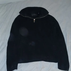 Svart stickad half zip från Jack & Jones - Svart stickad tröja från Jack & Jones med hög krage och half zip-dragkedja. Långärmad modell i klassisk passform, perfekt för lager-på-lager. Enkel och stilren design som funkar till det mesta.