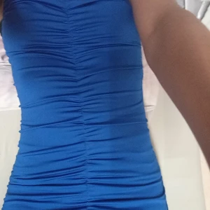 Blå SHEIN klänning  - Snygg blå kortklänning från SHEIN med smala axelband och rynkade detaljer framtill och baktill. Klänningen är figurnära och har en stretchig känsla, perfekt för dig som gillar en trendig och enkel look.