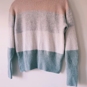 Randig stickad tröja från H&M LOGG XS - Supermysig stickad tröja från H&M LOGG i storlek XS. Tröjan har breda ränder i ljusrosa, grått, vitt och ljusgrönt. Den är långärmad och har ribbade muddar och nederkant. Perfekt för dig som gillar en chill och stilren look.  Helt & fint skick dock noppror