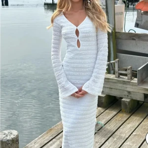 Vit långklänning med v-ringning - Superfin vit långklänning med v-ringning och unik cut-out framtill. Klänningen har långa utsvängda ärmar och ett vågigt, strukturerat mönster i tyget. Finns inte att köpa hos Nelly länge 