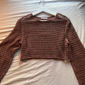 Brun croppad stickad tröja Zara - Säljer en brun croppad stickad tröja från Zara. Tröjan har ett grovmaskigt, luftigt mönster och långa ärmar. 