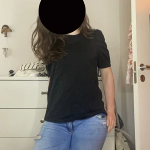 Svart basic t-shirt med puffärm - En svart t-shirt med korta puffärmar och rund hals. Modellen är rak och har en enkel, stilren look som passar till det mesta. T-shirten är i mjuk bomull och har en normal passform. Perfekt att matcha med jeans eller kjol.❤️