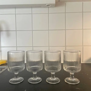 Dryckes glas 4st - Bilderna visar fyra stycken glas med fot och räfflad yta. Glasen har en modern och stilren design som passar perfekt för dig som vill ha snygga glas till festen eller vardagen. Perfekta för drycker och ger en trendig känsla till dukningen.