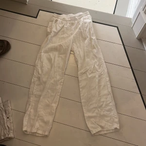 Vita linnebyxor med snörning från Lindex - Snygga och luftiga vita linnebyxor från Lindex med elastisk midja och snörning. Perfekta för varma dagar, med avslappnad passform och raka ben. Byxorna har fickor i sidorna och är tillverkade i mjukt linnematerial.