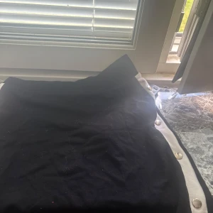 Svart kjol med vita detaljer  - Svart kortkjol från lindex med vita kanter och silvriga knappar längs sidorna🌸