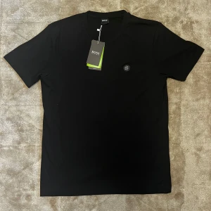 BOSS T-Shirt - Säljer en svart BOSS T-shirt med liten logga på bröstet. Tröjan är helt sjuk i kvalité - känns lyxig, sval och är nästan omöjlig att skrynkla. Väldigt stilren och passar till allt, både vardag och finare tillfällen.  Pris kan diskuteras!