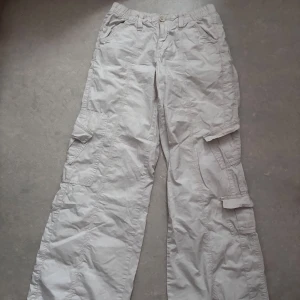 Y2K lowwaist cargobyxor  - Säljer ett par beige Y2K cargo pants från BDG Urban Outfitters. Byxorna har flera stora fickor på sidorna, elastisk midja och avslappnad passform. Materialet är lätt och skönt, använda ett par gånger inga defekter förutom att de är skrynkliga🤗
