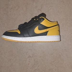 Nike Air Jordan 1 Low - 10/10 skick                                           ENDAST 599kr!                                       Köpt för ca 1200kr                           Snygga Nike Air Jordan 1 Low sneakers i svart och gul skinn med klassisk vit sula. Skorna har svarta snören, perforerad tå och ikoniska Jordan Wings-loggan på hälen. Perfekt för sommaren!
